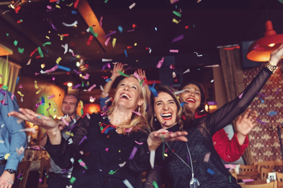 group of friends celebrating New Year's Eve with confetti dropping from ceiling